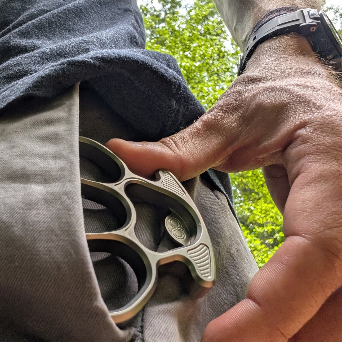 Person holding a bottle opener with a green outdoor background